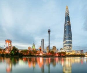 Wonderful evening view of skyscraper by lake at downtown of Seoul in South Korea. Amazing modern tower on blue sky background. Colorful city lights reflected in water. Beautiful cityscape.